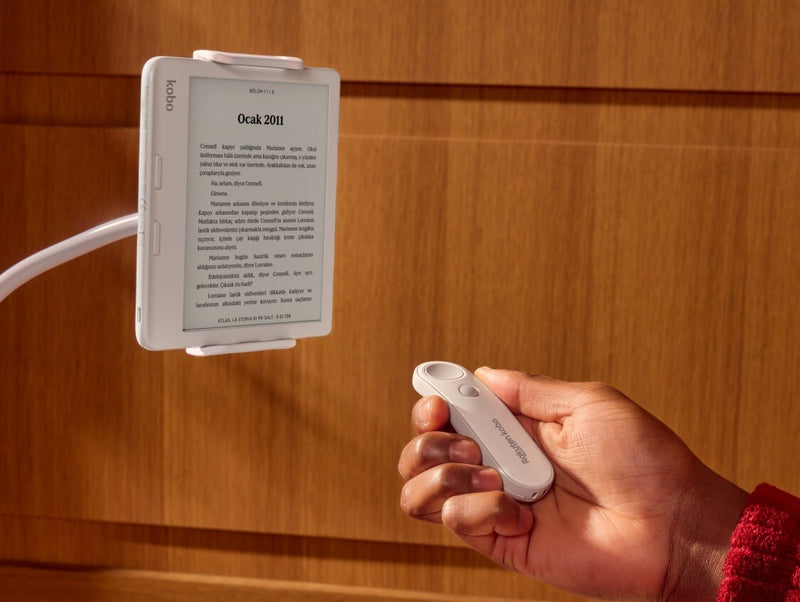 Beyaz bir Kobo Remote, birinin sağ elinde, bükülebilir bir stant üzerindeki beyaz bir Kobo Libra Colour e-kitap okuyucusuna doğru işaret ederken gösteriliyor.